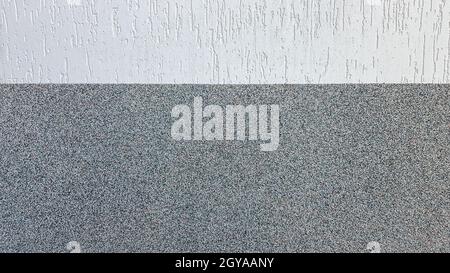 Des éclats de marbre gris et du stuc lumineux décoratif sur le mur divisé par une ligne horizontale.Arrière-plan de la façade du bâtiment.Texture stuc dans la rue. Banque D'Images