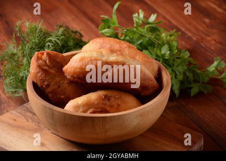 Viandes russes (Pasties, Hot cakes, Pirozhki, tartes) sur placard en bois. Tartes frites maison traditionnelles avec pommes de terre Banque D'Images