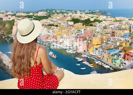 Belle jeune femme touristique bénéficiant d'une vue sur le port de Marina di Corricella et le village de l'île de Procida, Italie. Procida est la capitale italienne o Banque D'Images