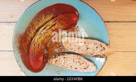 Currywurst allemand traditionnel dans une assiette sur une table en bois dans un café avec du pain. Vue de dessus. Spécialités d'Allemagne et de Berlin. Saucisse épicée Banque D'Images