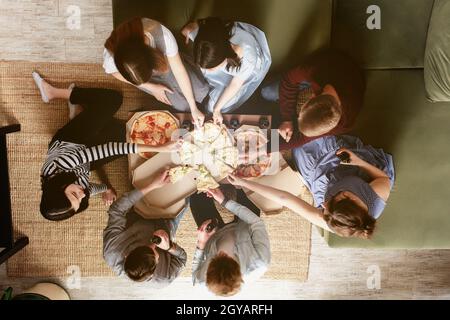 Une fête de pizza, un groupe d'amis bavardant et mangeant volontiers de la pizza à la table et de boire de l'eau douce de soda. Vue de dessus du deuxième étage. Nombreux ven Banque D'Images