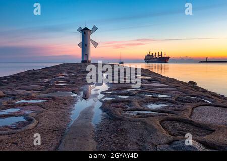 Mer Baltique et Stawa Mlyny, balise de navigation en forme de moulin à vent au coucher du soleil, symbole officiel de Swinoujscie, Pologne Banque D'Images