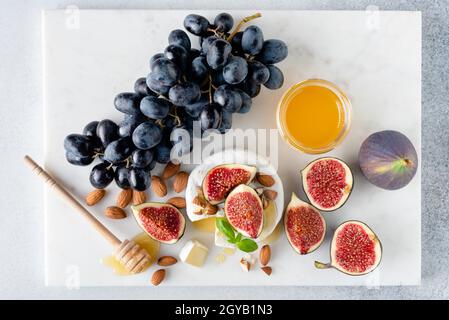 Plateau de fromages Camembert avec figues, raisins, noix et miel.Arrière-plan en marbre, vue du dessus Banque D'Images
