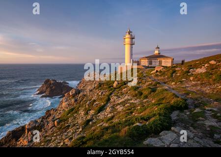 Vue sur le paysage marin du phare du Cap Tourinan au coucher du soleil avec des nuages roses, en Espagne Banque D'Images