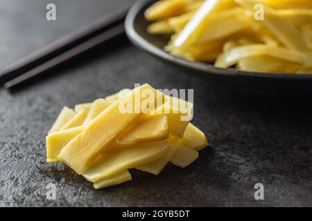 Tranches de pousses de bambou en conserve sur table noire. Banque D'Images