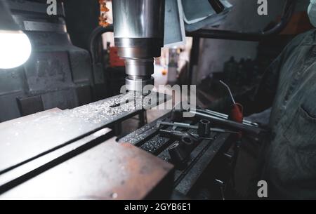 Fraiseuse travaillant près d'un travailleur avec un masque de protection. Outil pour la pièce de métal coupée. Fraiseuse verticale avec fraise en carbure de tungstène Banque D'Images