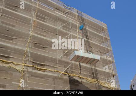 Grue avec charge de panneaux de cloison sèche sur le chantier de construction. Travailler sous un concept de charge suspendue Banque D'Images