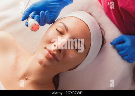 Soin beauté du visage. Femme faisant une luminothérapie à LED rouge. Banque D'Images