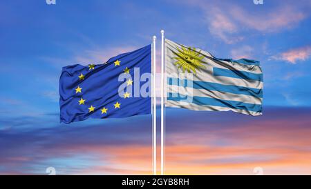 Union européenne et Uruguay deux drapeaux sur les mâts et le bleu ciel nuageux Banque D'Images