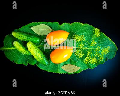 Légumes concombres et tomates avec feuille de raifort sur fond noir. Photo de nourriture. Plats végétariens. Agriculture. Ferme. Boutique photo de fenêtre. Pression Banque D'Images