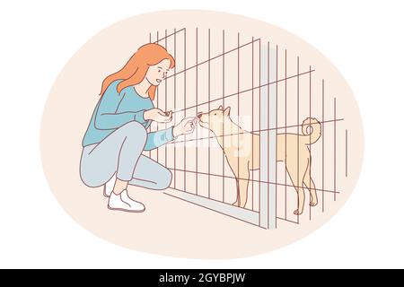 Les chiens de l'abri, le bénévolat, aider les animaux concept. Jeune fille heureuse personnage de dessin animé assis et donnant snack au chien dans la cage dans l'abri Banque D'Images