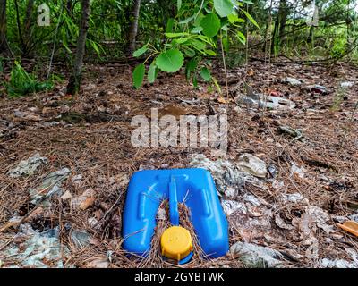 La cartouche en plastique bleu est enterrée dans le sol. Récipient pour produits chimiques. Couvercle jaune. Produits chimiques automobiles. Pollution de l'environnement. Déchets de plastique Banque D'Images