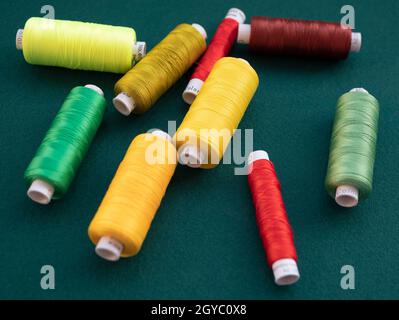 Bobines de fil multicolore pour la couture et la broderie sur fond vert.Fils pour machine à coudre et serrure à l'atelier Banque D'Images