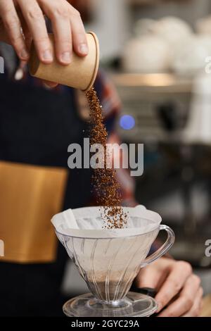 mains de sexe masculin versant du café moulu dans le filtre pour préparer un espresso Banque D'Images