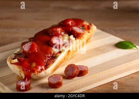 Mini pizza avec saucisses et ketchup de tomate sur une planche à découper en bois Banque D'Images