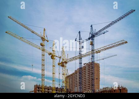 les grues de construction érigent un bâtiment de plusieurs étages. Banque D'Images