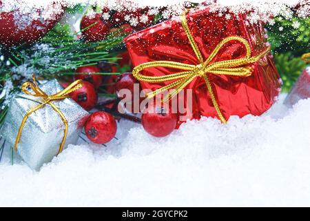 Cadeaux de Noël et les baies niché dans la neige Banque D'Images
