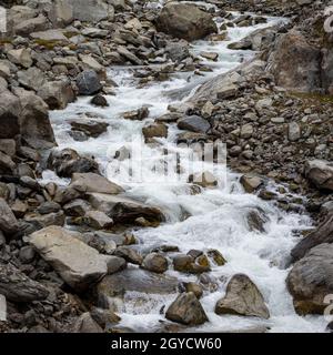 Glacier d'Oberaletsch : une rivière d'eau froide qui coule sur un paysage de roche stérile et de granit dans les montagnes de la Suisse. Banque D'Images