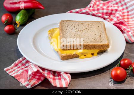 Toast au cheddar dans une assiette en porcelaine blanche sur une table en pierre sombre Banque D'Images