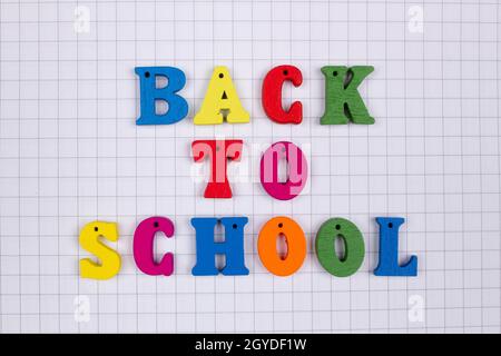 Inscription des mots du slogan Retour à l'école en lettres multicolores sur un fond carré de bloc-notes d'école.Lettres colorées Banque D'Images