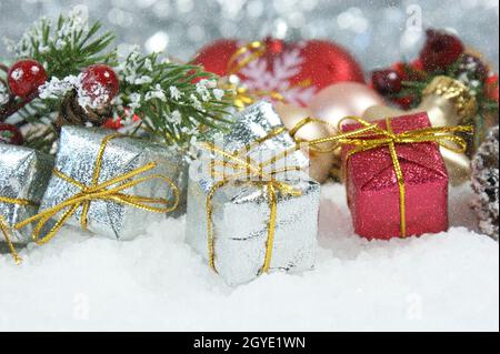 Cadeaux de Noël et branche de pin nichée dans la neige Banque D'Images