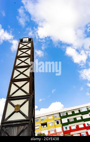le lampadaire d'une ville en forme de monolithe indique un ciel bleu avec des nuages blancs et des bâtiments colorés Banque D'Images