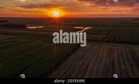 Coucher de soleil coloré au-dessus de la forêt et des champs aériens avec le soleil et les stations éoliennes lointaines, Podlaskie Voivodeship, Pologne, Europe Banque D'Images