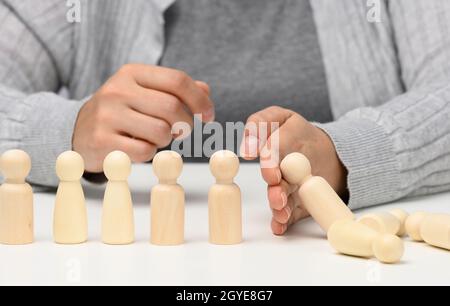 la main arrête la chute des figurines d'hommes sur un fond blanc. Concept d'une personnalité forte et courageuse capable de résister à l'inégalité difficile Banque D'Images