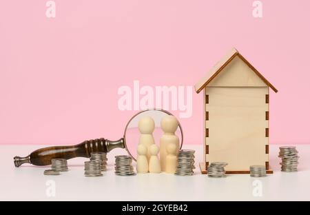 figurines en bois d'une famille, piles d'argent métallique, maison miniature en bois. Achat immobilier, concept hypothécaire. Accumulation de fonds Banque D'Images