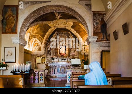 Vérone, Italie - 20 septembre 2021 : une nonne en raies blanches assise sur un banc dans un ermitage italien. Banque D'Images