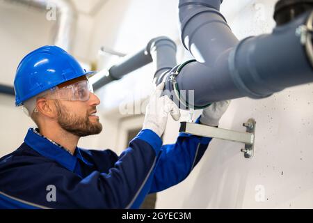 Inspection des tuyaux d'eau en PVC par un travailleur de la construction Banque D'Images