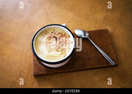 Une tasse de Cappuccino se dresse sur une table en bois et représente une cuillère. Banque D'Images