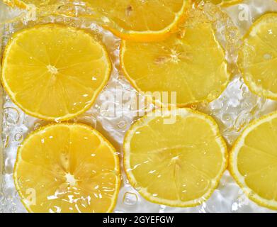 Gros plan de tranches fraîches de citron jaune sur fond blanc.Tranches de citron dans l'eau pétillante sur fond blanc, gros plan.Citron soda. Banque D'Images