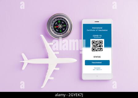 Modèle d'avion, passeport et carte d'immunité sont arrangés application sur smartphone sur fond violet, concept de Voyage pendant la digita pandémique Covid-19 Banque D'Images