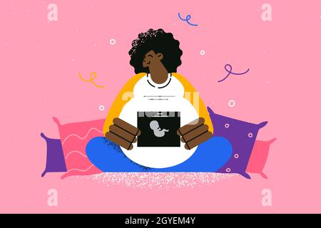 Concept de maternité et de maternité heureux.Jeune femme enceinte noire souriante démontrant sa sonographie de bébé, assise sur le lit à la maison, se sentant heureuse Banque D'Images