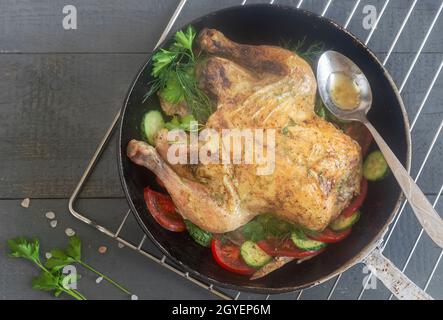 Le poulet frit avec des concombres, des tomates et du persil est sur la table dans une poêle en fonte. Vue de dessus, gros plan Banque D'Images