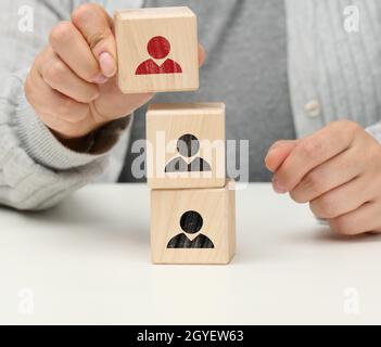 la main femelle tient un cube en bois avec un homme. Le concept de trouver un leader, un employé talentueux, une hiérarchie au sein de l'équipe Banque D'Images