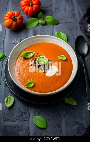 Soupe de tomates maison avec aubergines rôties et basilic sur fond sombre Banque D'Images