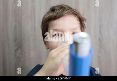 Enfant garçon utilisant un spray médical pour respirer. Inhalateur, espaceur et masque. Vue avant Banque D'Images