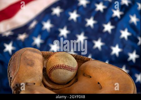 Gros plan d'un vieux baseball et gant contre le drapeau américain met en évidence l'un des sports les plus populaires du pays. Banque D'Images