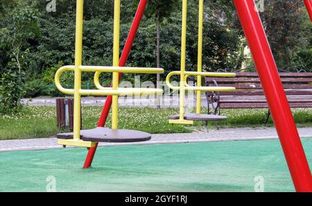 Aire de jeux moderne fermée. Mesures de sécurité et de protection contre la COVID-19 dans le parc de la ville. Bébé vide jaune métal balançoire dans le parc sans personnes Banque D'Images