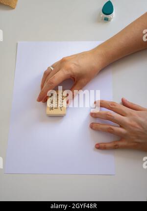 les mains des femmes plaçant un timbre d'emballage durable sur une feuille de papier vierge Banque D'Images