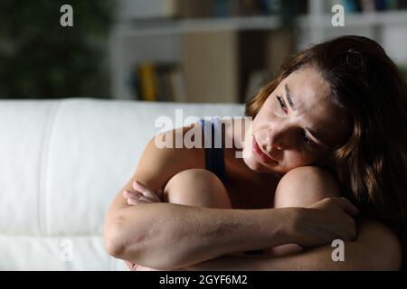 Une triste femme se plaint de regarder loin assis sur le sol dans le salon à la maison la nuit Banque D'Images