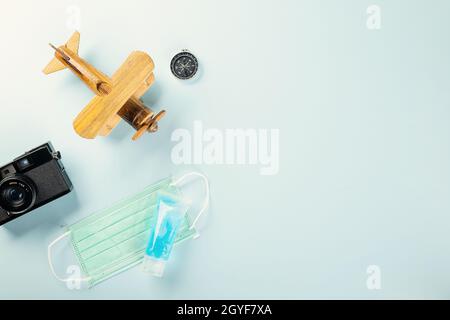 Journée mondiale du tourisme pendant la pandémie de coronavirus, avion modèle avec masque et appareil photo, STOP et concept de voyage sûr, studio tourné en fond bleu wi Banque D'Images