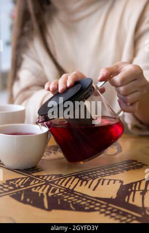 Versez le thé chaud dans une tasse. La tasse de thé sur la table en bois a été éclairée par la lumière douce du soleil qui a pénétré l'atmosphère chaude Banque D'Images