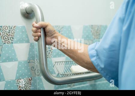 Asiatique senior ou âgée vieille femme patiente utiliser la pente passerelle de la poignée de sécurité avec aide assistant de soutien dans la salle de soins infirmiers de l'hôpital, sain fort Banque D'Images