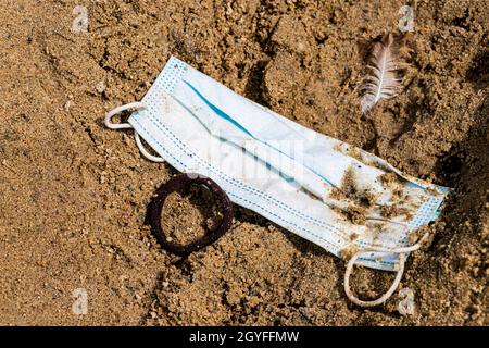 Les déchets sales masques chirurgicaux sur sable de plage dans la nature. Pollution par le virus Corona. Banque D'Images