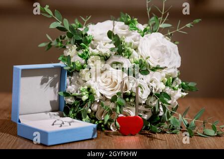Composition des détails du matin de la mariée.Vue de dessus des anneaux de mariage, beau bouquet de fleurs roses avec rubans.Pose à plat. Banque D'Images