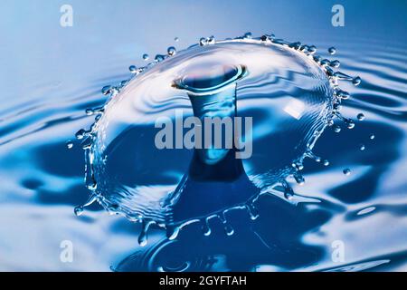 De grandes éclaboussures et des ondulations lorsque deux gouttes d'eau frappent dans l'air sur l'eau bleue Banque D'Images