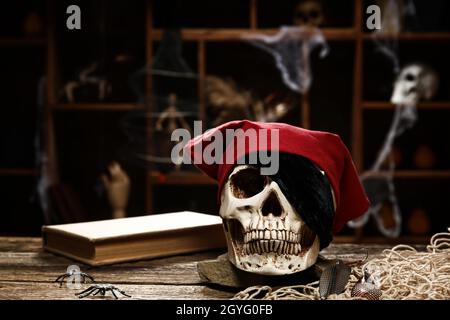 Crâne pirate avec livre sur table sur fond sombre Banque D'Images